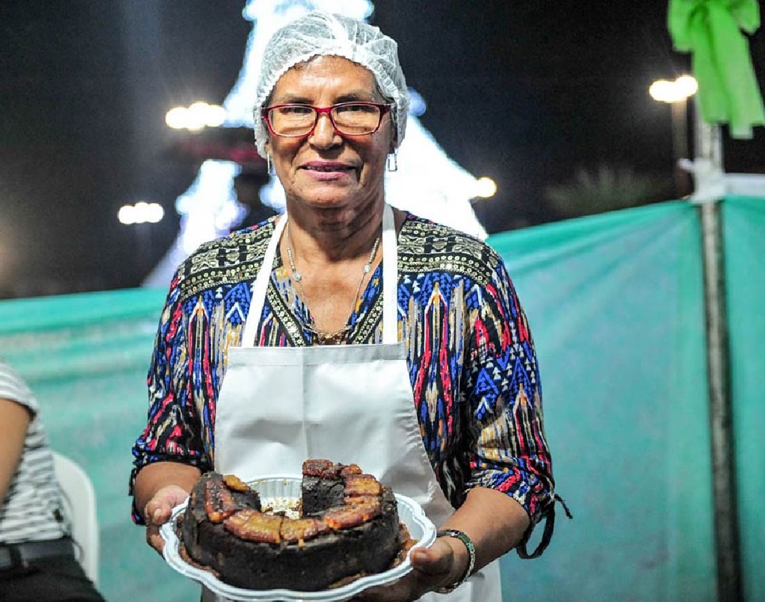 Dona Rai exibe com orgulho o bolo de banana, um dos doces que prepara à base do fruto