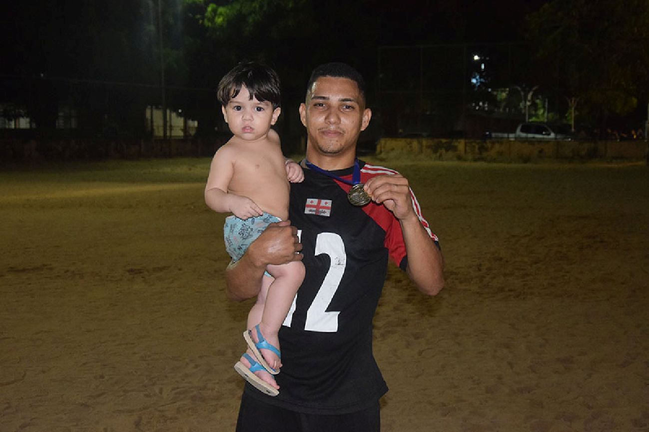 Eliseu Miranda segurando o filho e a medalha dos Jogos de Verão