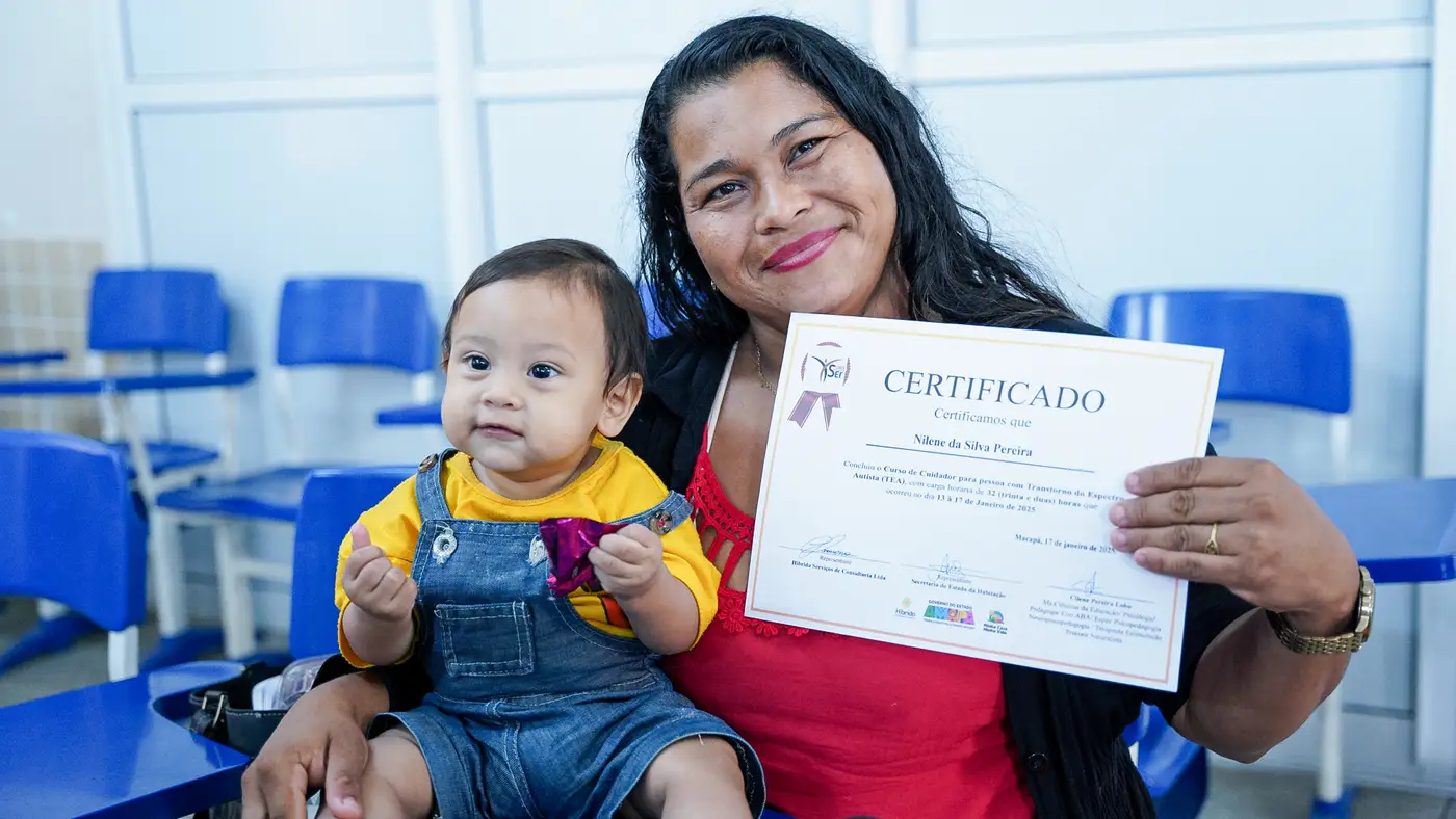 Mãe atípica, Nilene Pereira e seu filho Jadsom com seu certificado de cuidadora do Transtorno do Espectro Autista (TEA)