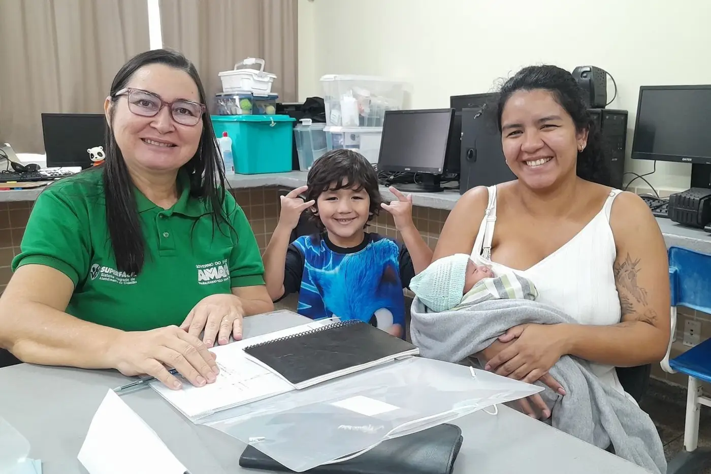 O pequeno Júlio, sua mãe Ana Luiza e seu irmãozinho sendo atendidos pela servidora Rosineide