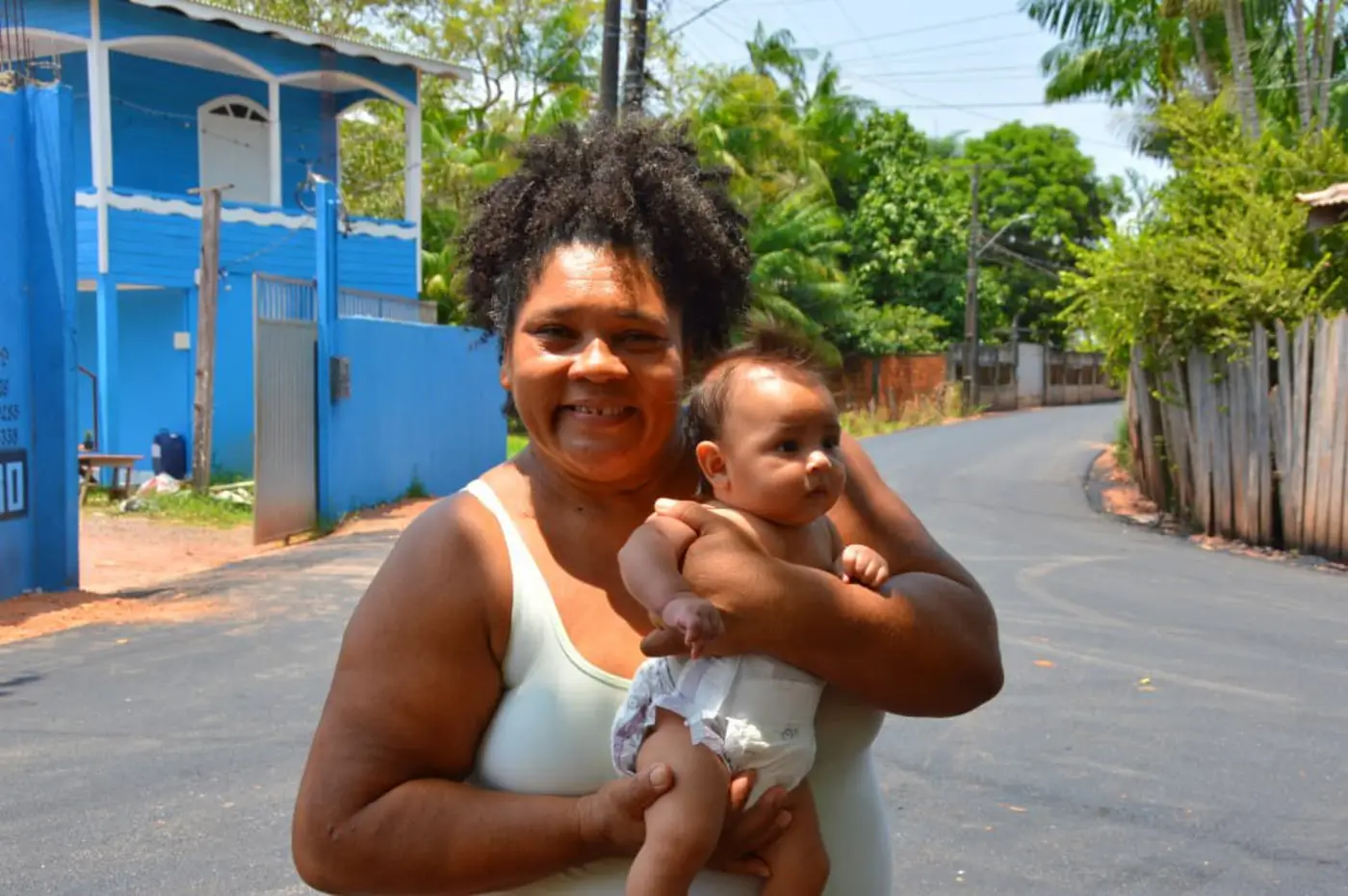 A dona de casa Maria Madalena comemora a chegada do asfalto na rua onde mora: ″antes era só lama e barro″