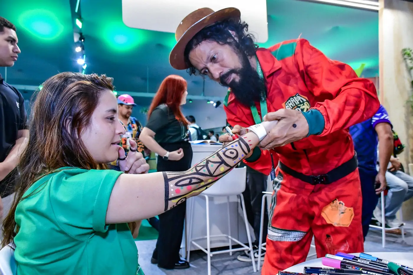 O artista Afrane Tavóra transforma visitantes em telas vivas, com desenhos inspirados nos elementos e nas cores da Amazônia