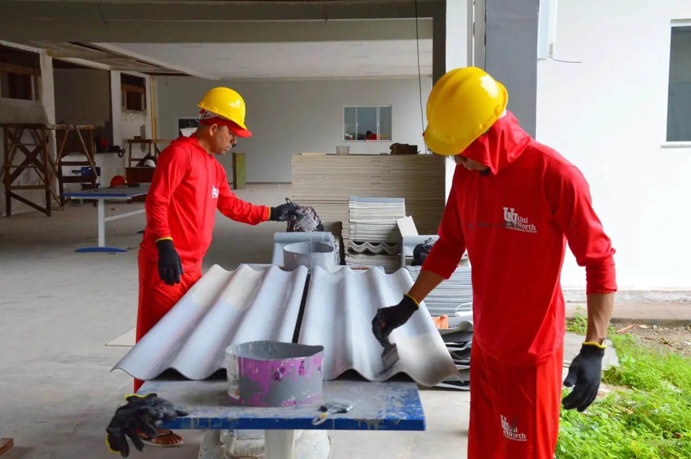 No canteiro de obras, as equipes atuam na finalização das janelas e portas em material composto de alumínio e vidro incolor